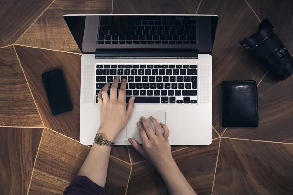 Laptop, phone, and wallet laid out on a desk